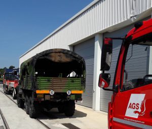 AGS Movers truck parked behind a military vehicle.