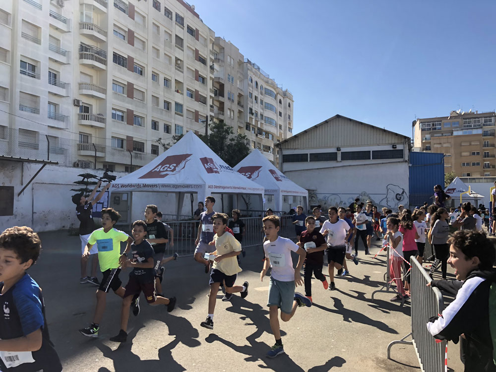 Kids running a race with AGS Movers branded tents in the background.